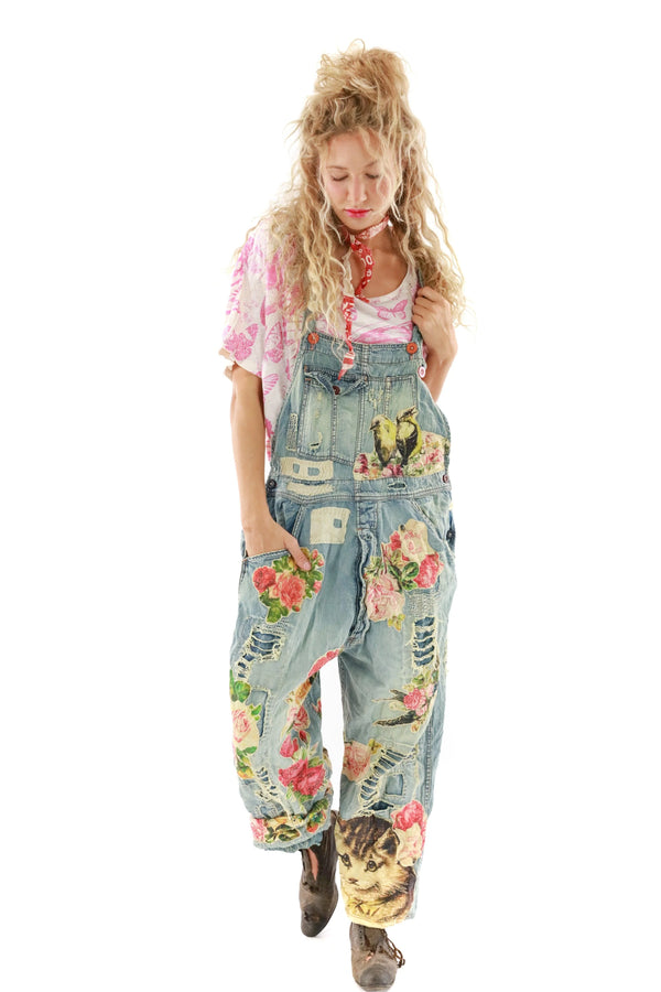 Woman wearing overalls with patch work all over as well as kittens, roses and birds throughout 