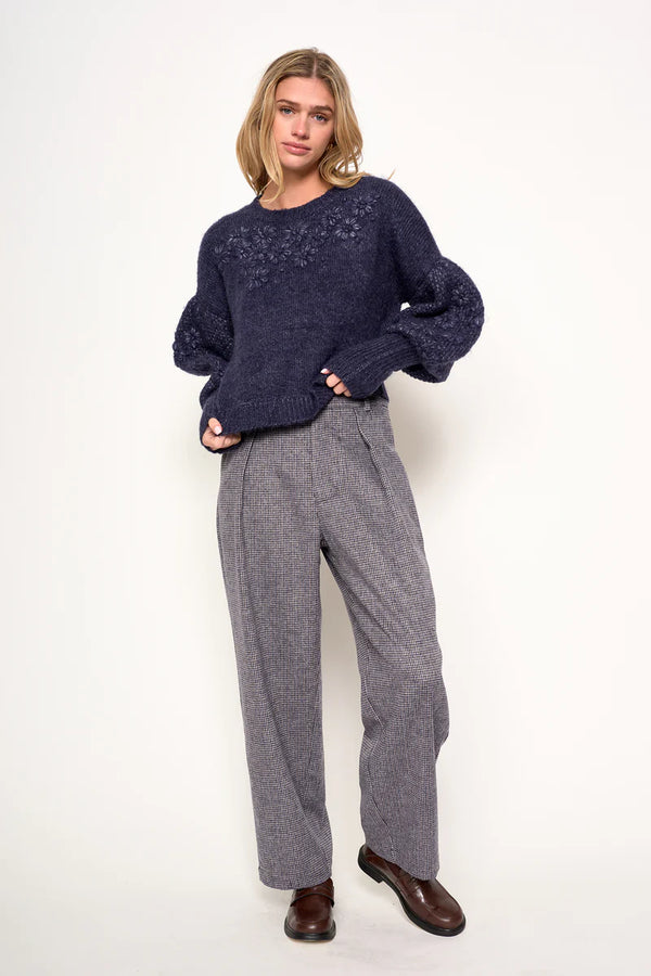 Woman wearing a navy sweater and gray pants on a white background