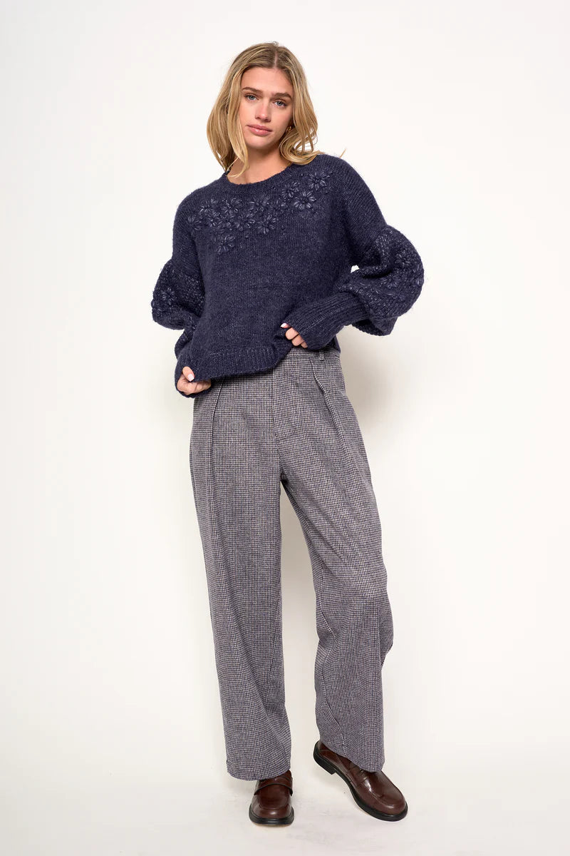 Woman wearing a navy sweater and gray pants on a white background