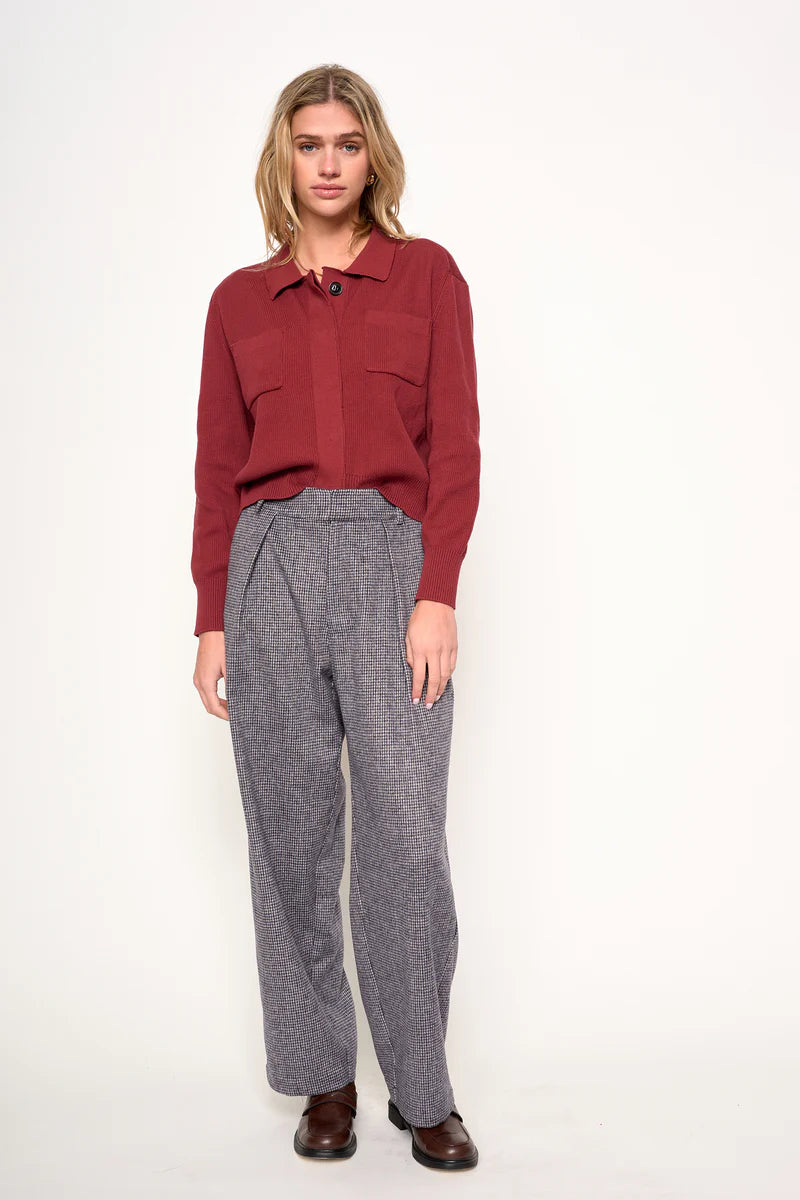 Woman wearing a red shirt and gray pants on a white background