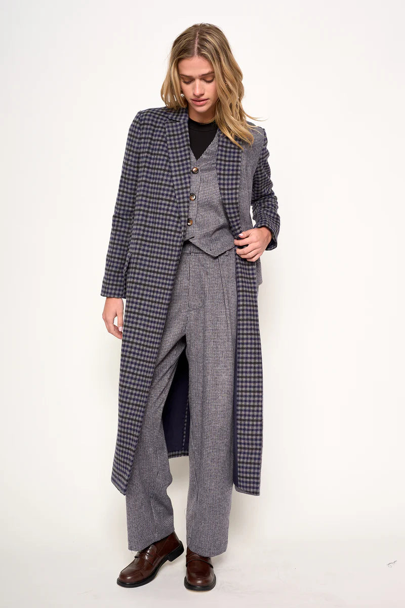 Person wearing a gray checkered coat over a suit on a white background