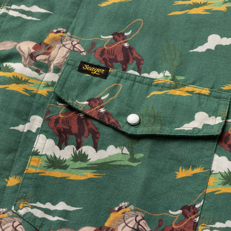 Green pearl snap shirt with double breast pockets and image of cowboy roping a steer repeated all over