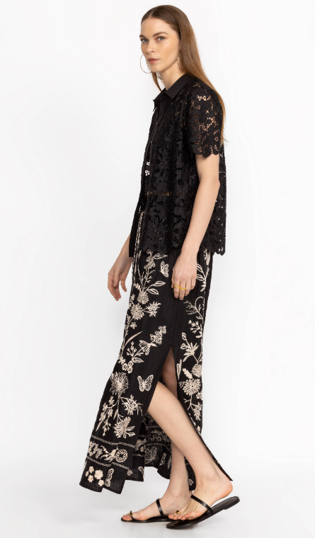 Woman wearing black maxi skirt with side slits and white floral embroidery all over
