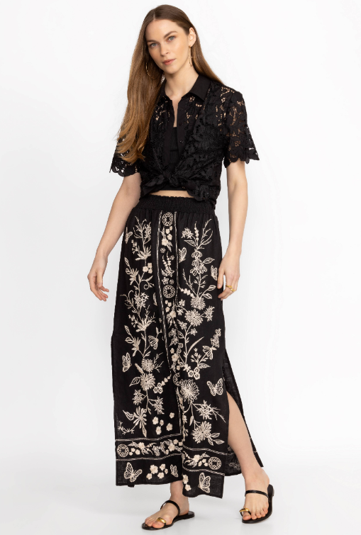 Woman wearing black maxi skirt with side slits and white floral embroidery all over