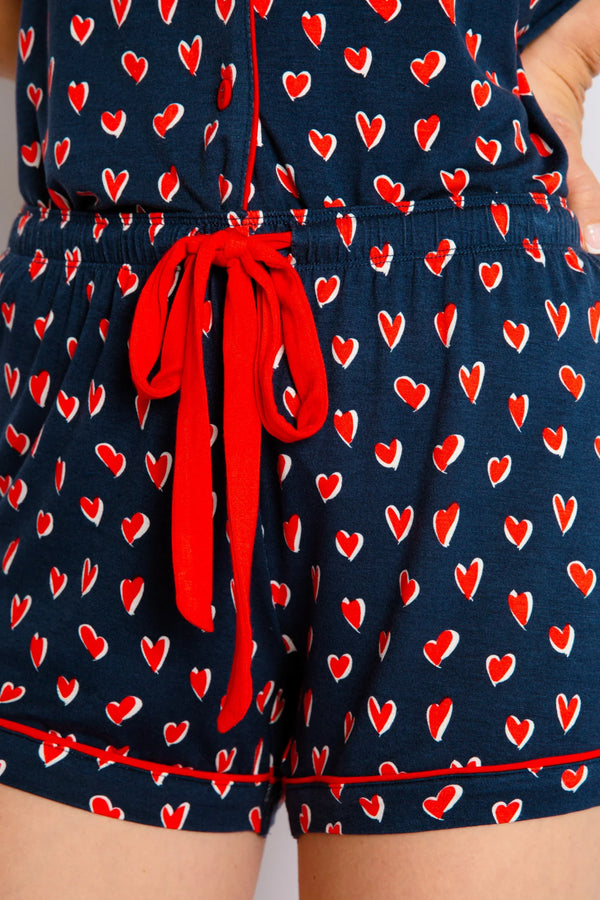 Woman wearing navy pj set with hearts all over.