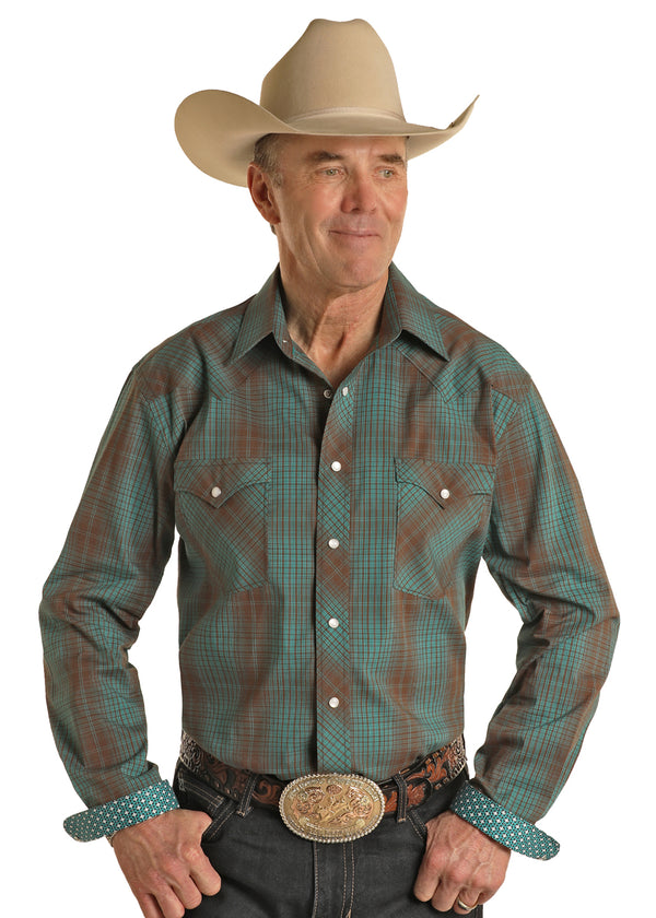 Man wearing turquoise and brown plaid long sleeve button down with double button breast pockets