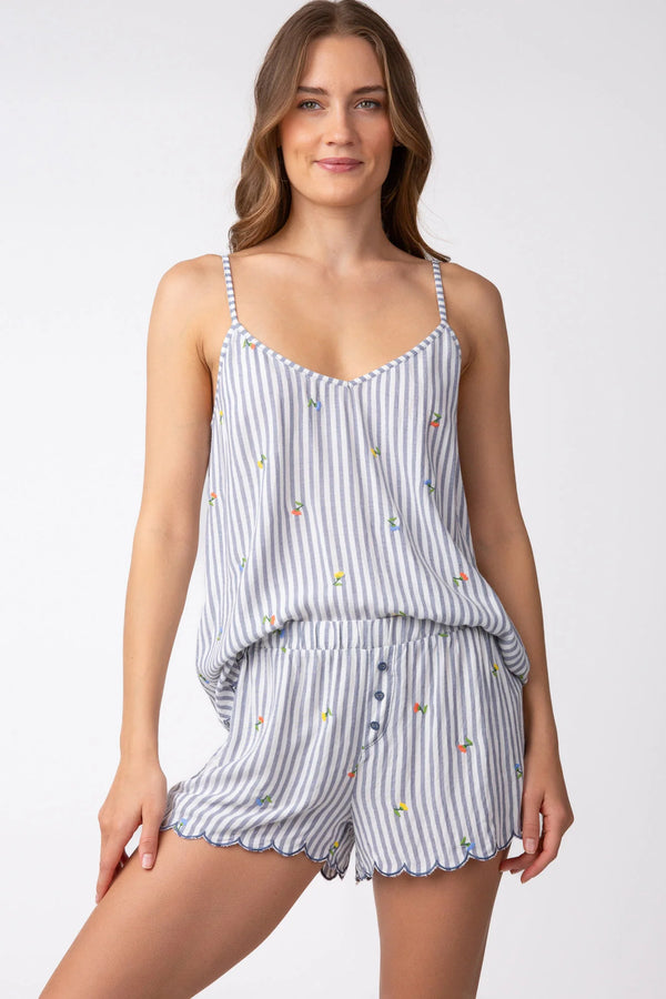 Woman wearing grey and white stripe pajama shorts with embroidered flowers all over and scallop hem detail