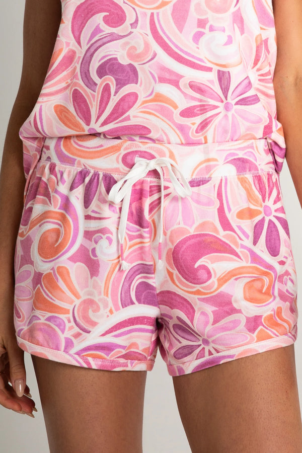 Woman wearing lounge shorts in a pink and orange colorway with floral pattern and paisley print throughout 
