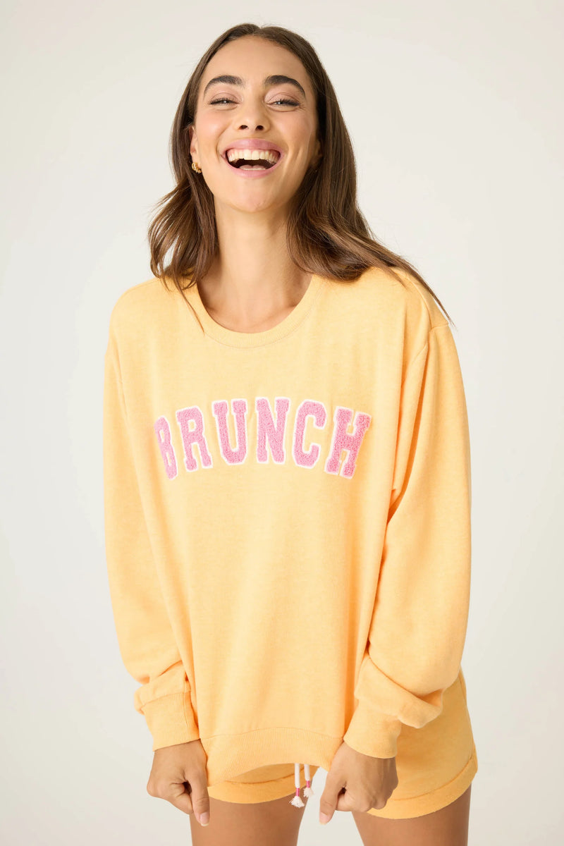 Woman wearing a yellow 'Brunch' sweatshirt on a white background