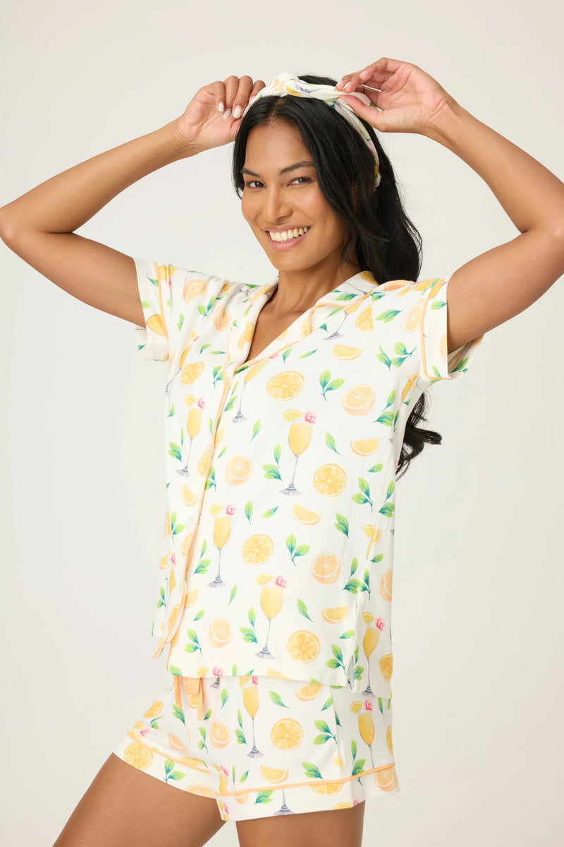 Woman wearing a orange and white pajama set with orange pattern on a plain background