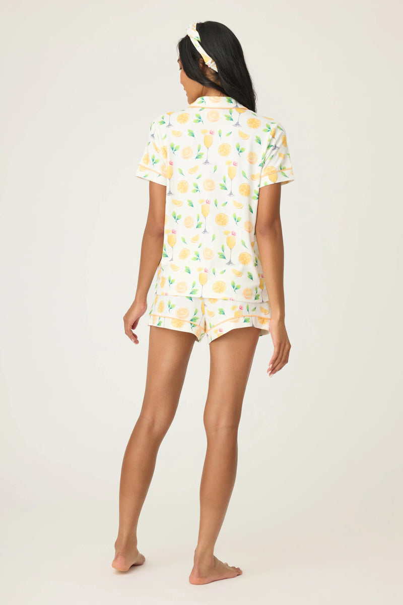 Woman wearing a orange patterned pajama set on a white background