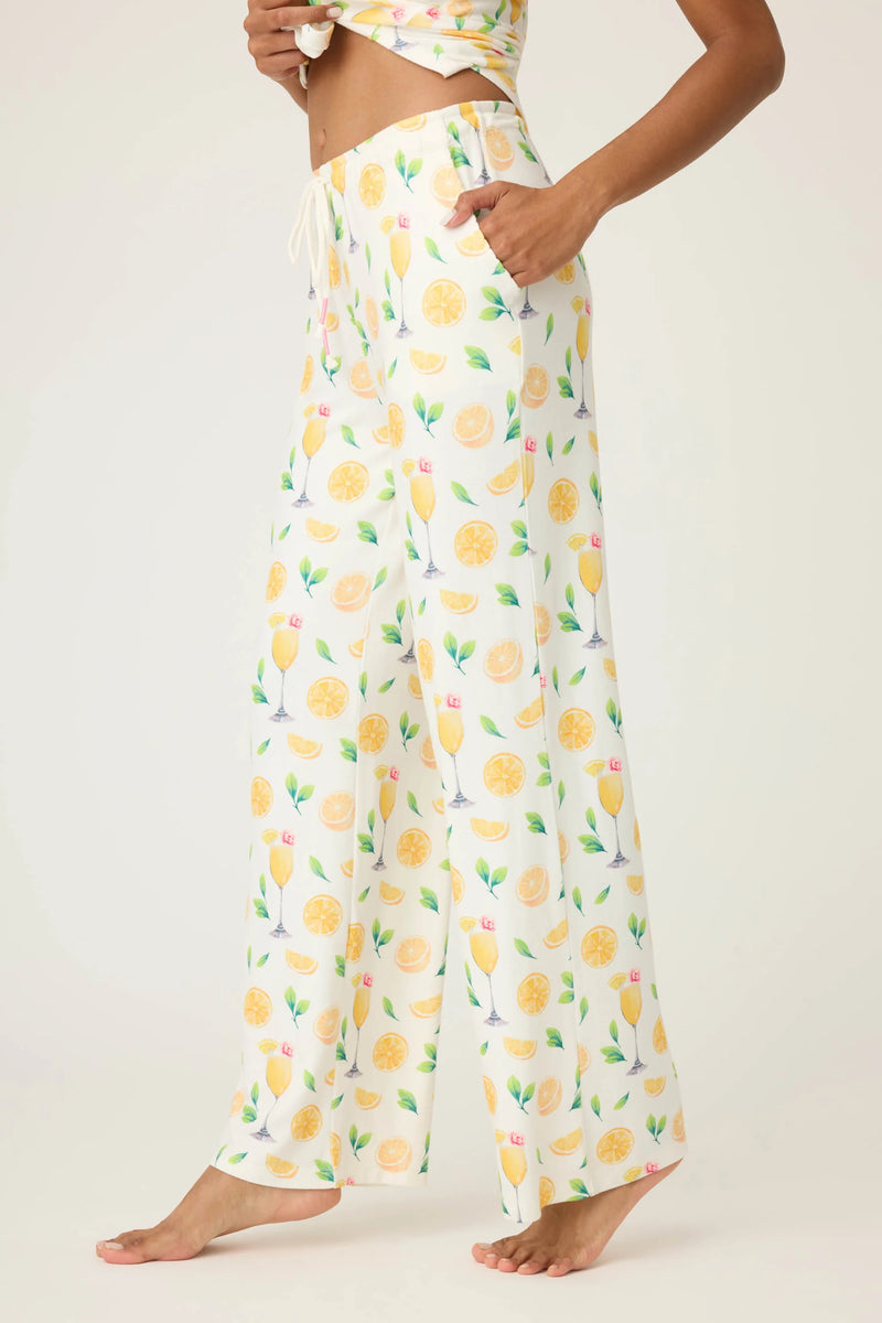 Person wearing a pair of wide-leg pants with lemon print on a white background