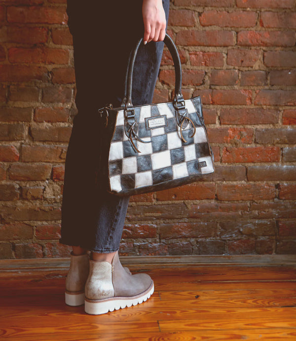 Black and white leather checker print purse with handle attached and cross body feature