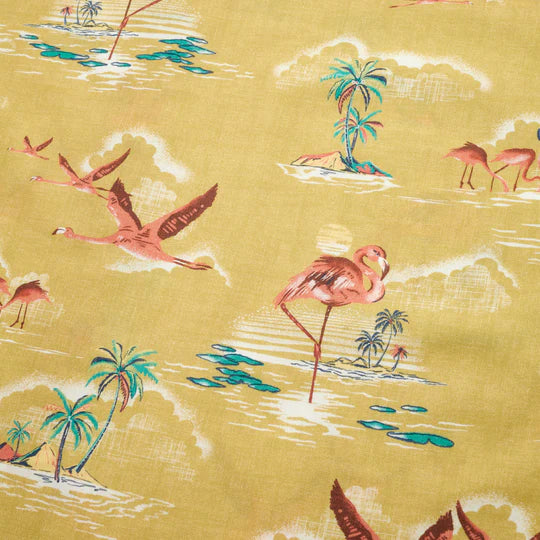 Yellow short sleeve button down shirt with pink flying flamingos and stationary flamingos standing in water near palm trees throughout