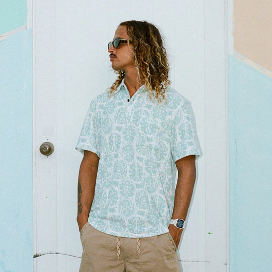 Men's shirt made from terrycloth and had a front breast pocket with collar and buttons at the top of the neck. The pattern is a Hawaiian floral print in a blue and white color way