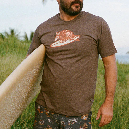 Brown short sleeve graphic tee with orange and cream armadillo riding a surf board