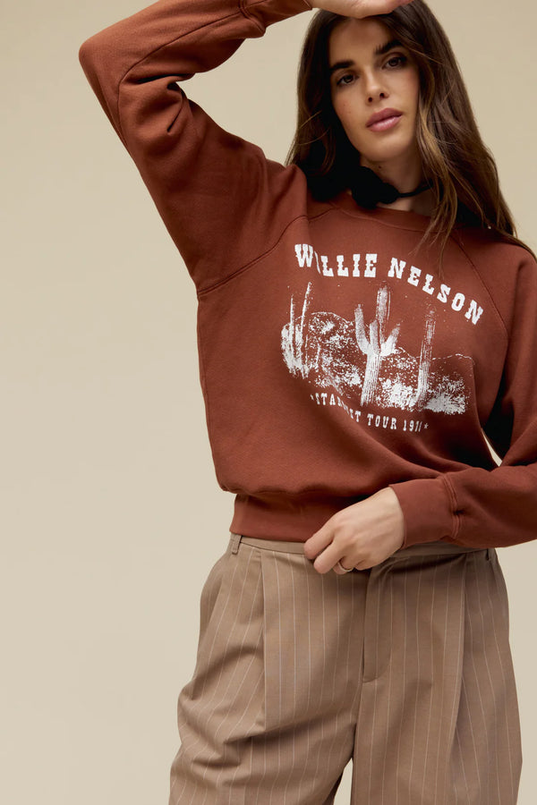 Woman wearing crewneck accented in crackle ink and designed with said stardust atop the living legend’s name, Willie Nelson, stamped in western letters