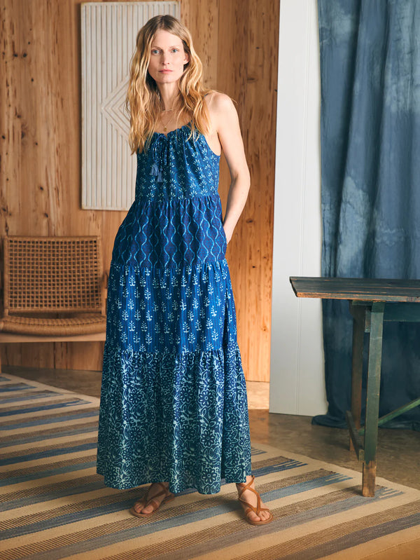 Woman wearing tiered maxi dress with various blue floral print, spaghetti straps and pockets