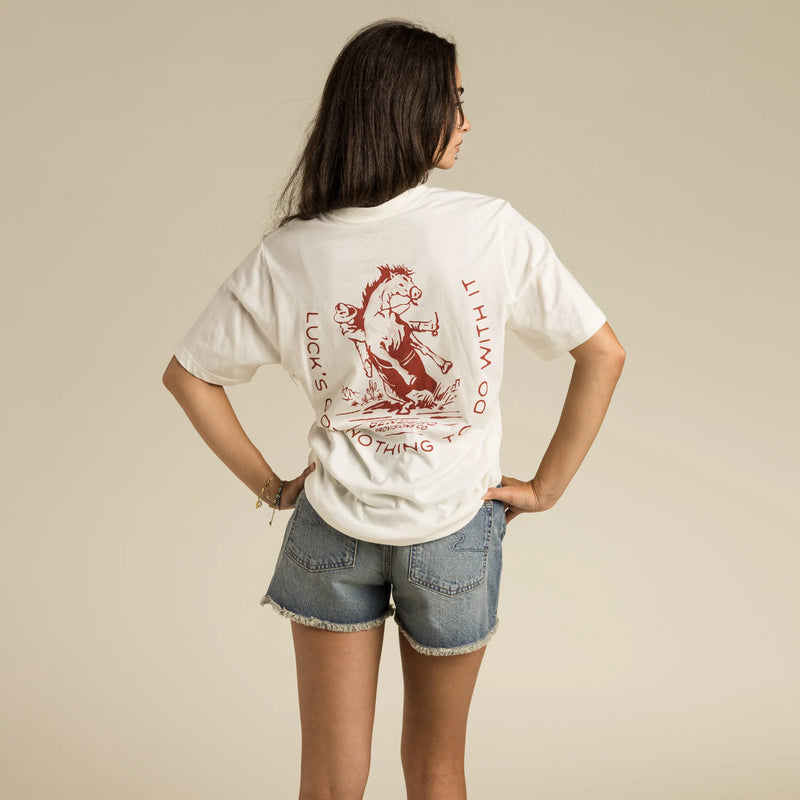 White short sleeve tee with graphic of a cowboy stopping suddenly on a horse with script "Luck's got nothing to do with it" around the image