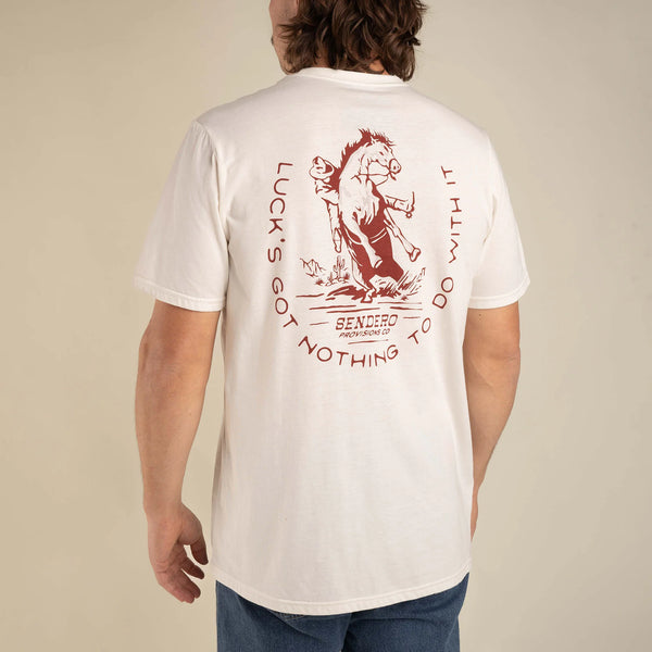 White short sleeve tee with graphic of a cowboy stopping suddenly on a horse with script "Luck's got nothing to do with it" around the image
