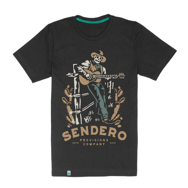 Deep grey color short sleeve t-shirt with image of skeleton cowboy leaning against a fence playing the guitar with script "Sendero Provisions Company ESTD 2014"