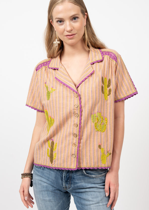 Woman wearing embroidered cacti on short sleeve shirt with button front top