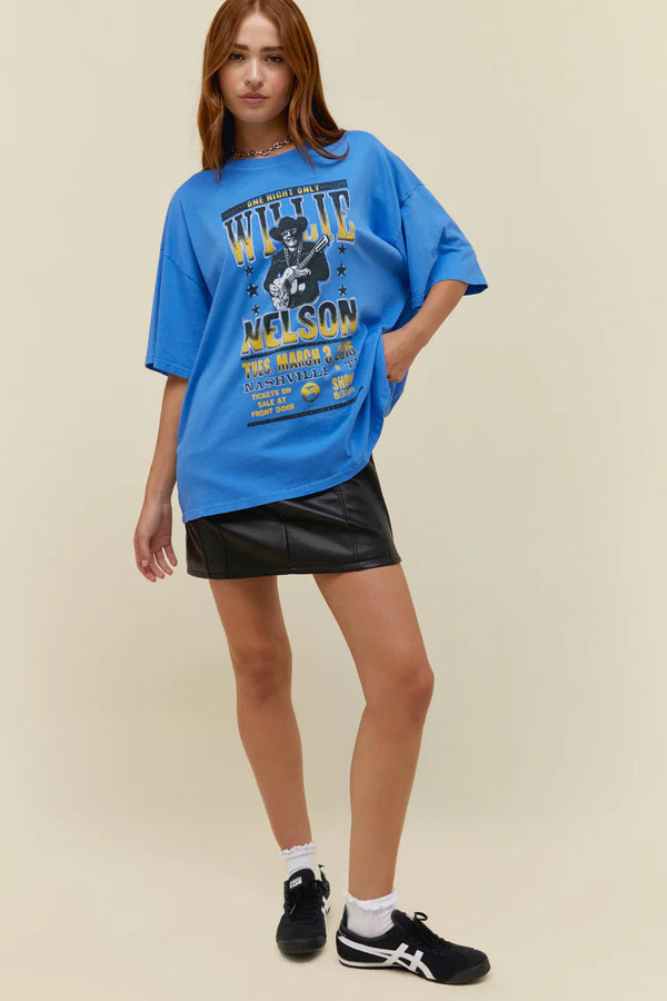 Woman wearing blue short sleeve tee with image of Willie Nelson and script from a concert ad