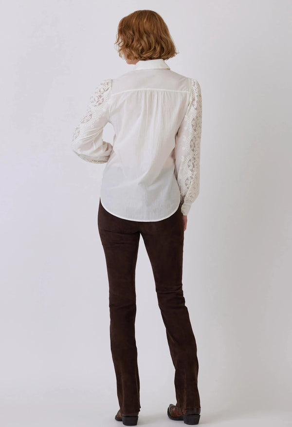 Woman wearing white button up lace blouse with lace detail on the sleeves and body of shirt