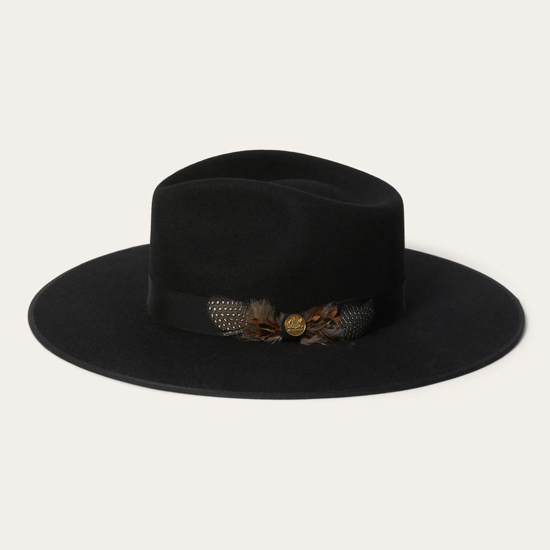 Black fedora hat with decorative band featuring feathers and a button on a light gray background