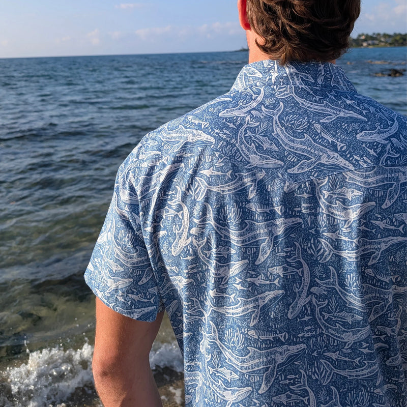 Person wearing a blue patterned shirt standing by the water