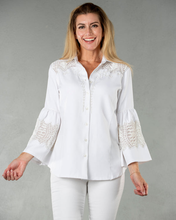 Woman wearing white button up blouse features a flowy fit and elegant bell sleeves with intricate lace detailing on the shoulders