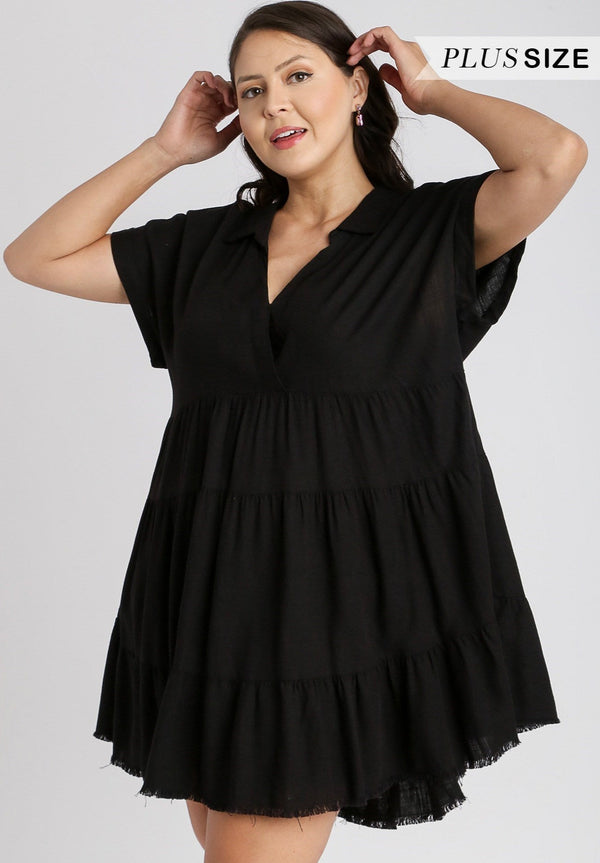 Woman wearing black mini dress with short sleeves, v-neck and tiered detail