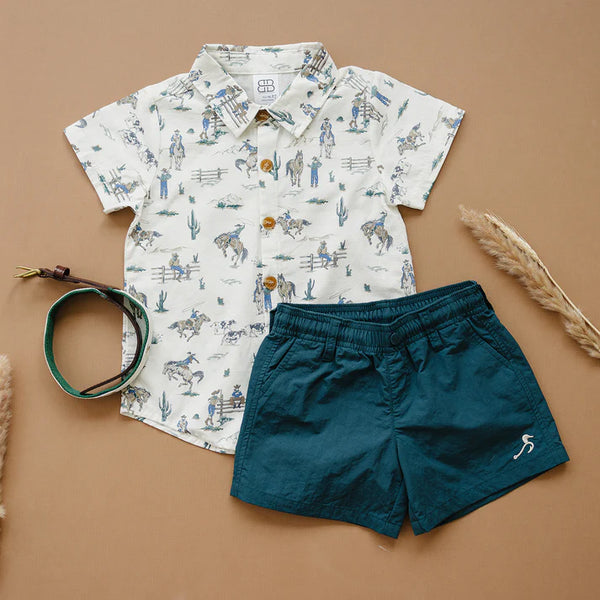 Children's shirt with horse print and blue shorts on a brown background