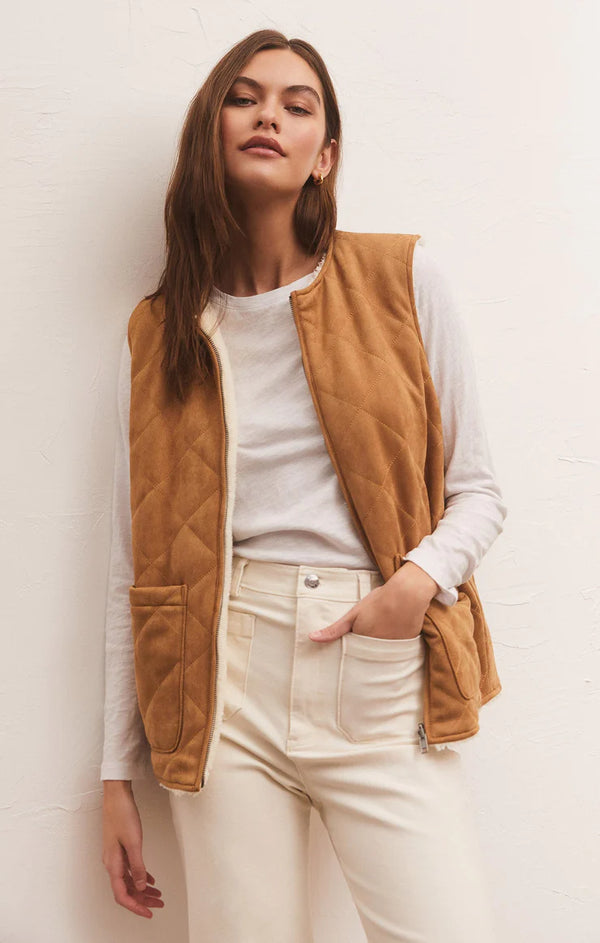 Woman wearing Faux Suede fabric on one side, and is a longer vest reverses to a plush sherpa. The front zips from top to bottom and features quilting detail and pockets.