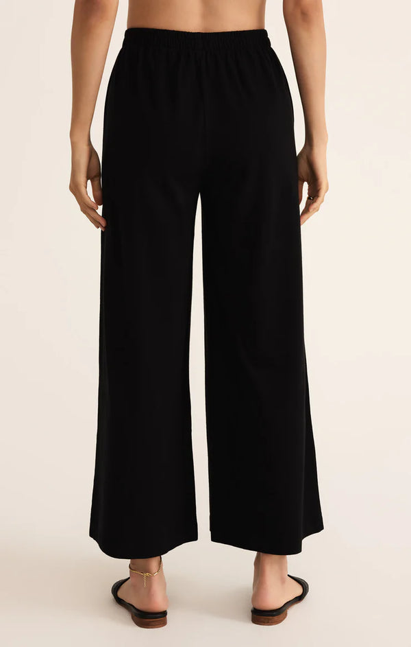 Black wide-leg pants worn by a person on a beige background