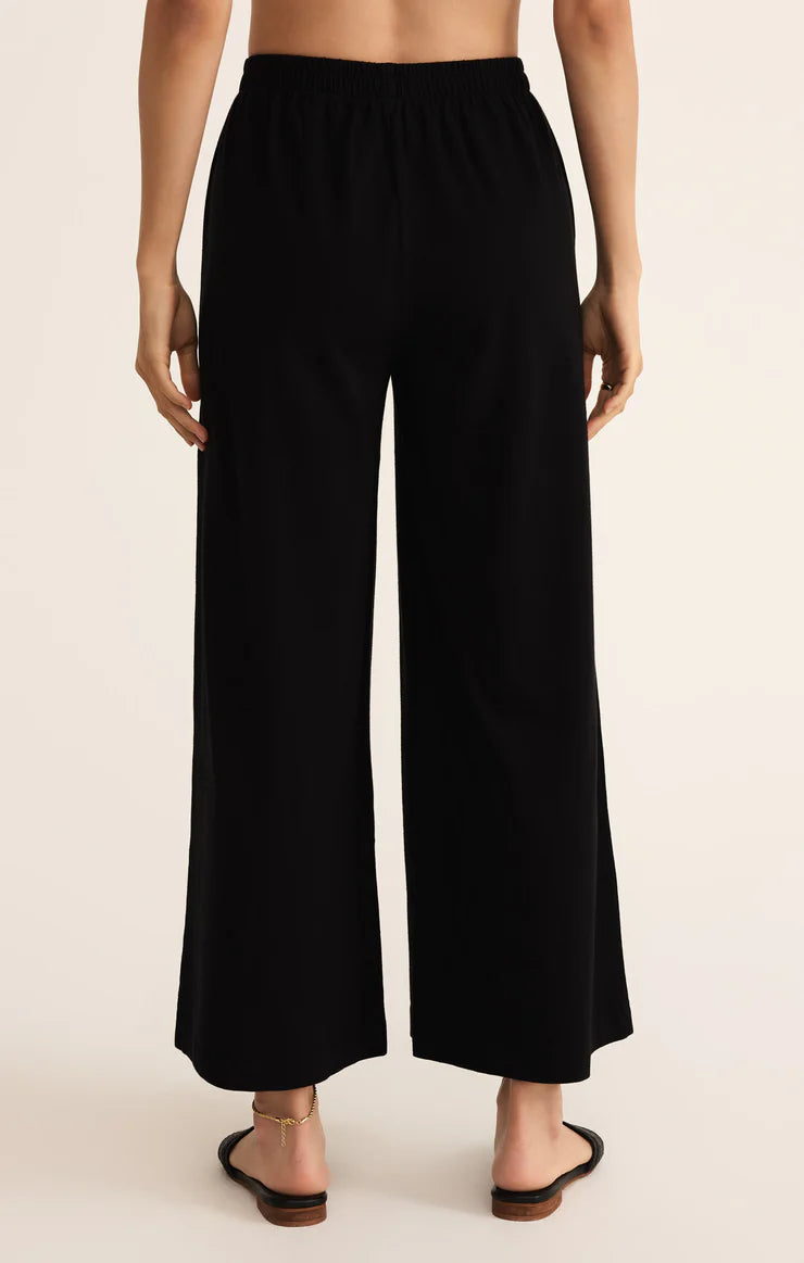 Black wide-leg pants worn by a person on a beige background