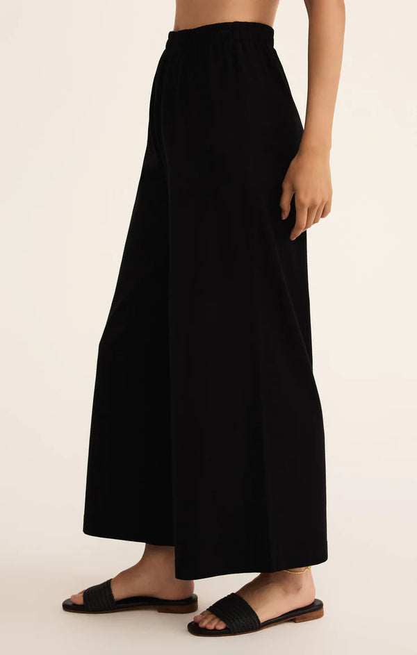 Black wide-leg pants worn by a person on a beige background