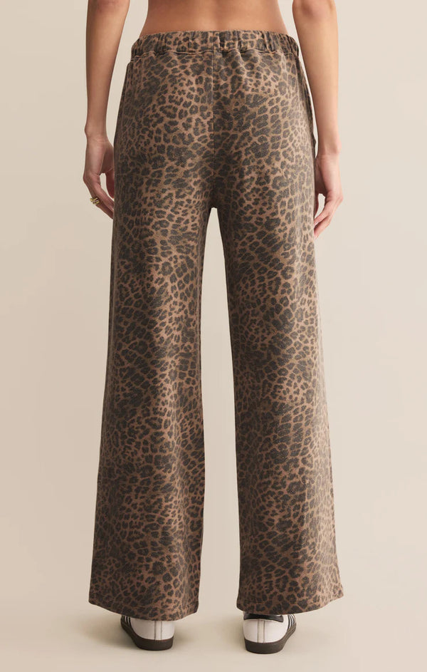 Leopard print pants worn by a person on a beige background
