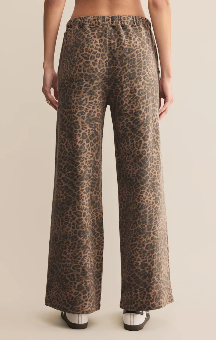 Leopard print pants worn by a person on a beige background