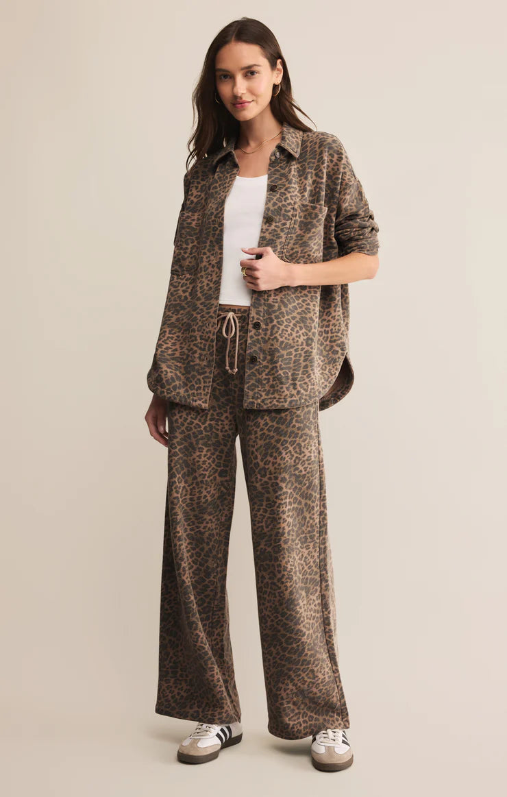 Woman wearing a patterned outfit with wide-leg pants and a jacket on a beige background