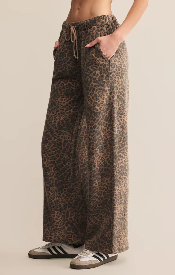 Leopard print pants worn by a person on a beige background