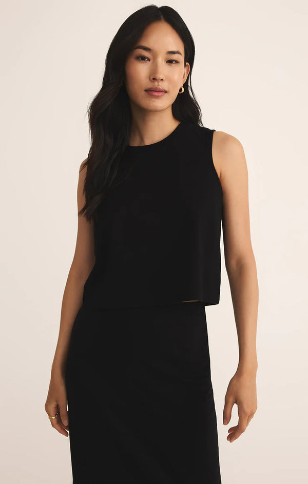 Woman wearing a black sleeveless top against a beige background