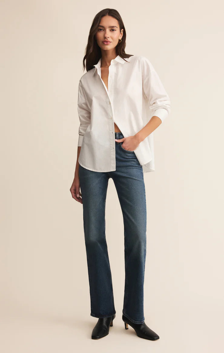 Woman wearing a white shirt and blue jeans on a beige background