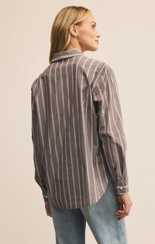 Woman wearing a striped shirt and jeans against a plain background