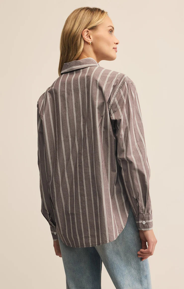 Woman wearing a striped shirt and jeans against a plain background
