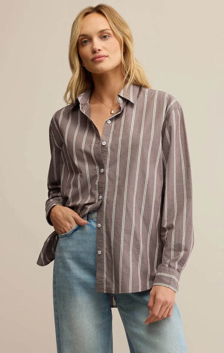 Woman wearing a striped shirt and jeans against a neutral background