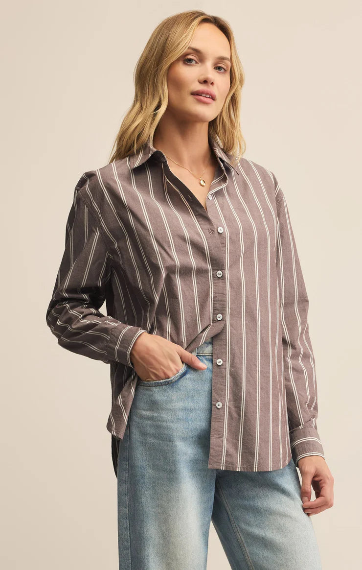 Woman wearing a striped shirt and jeans against a beige background