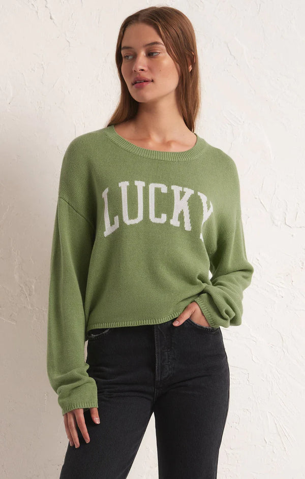 Woman wearing green sweater with white letters on front spelling "lucky"