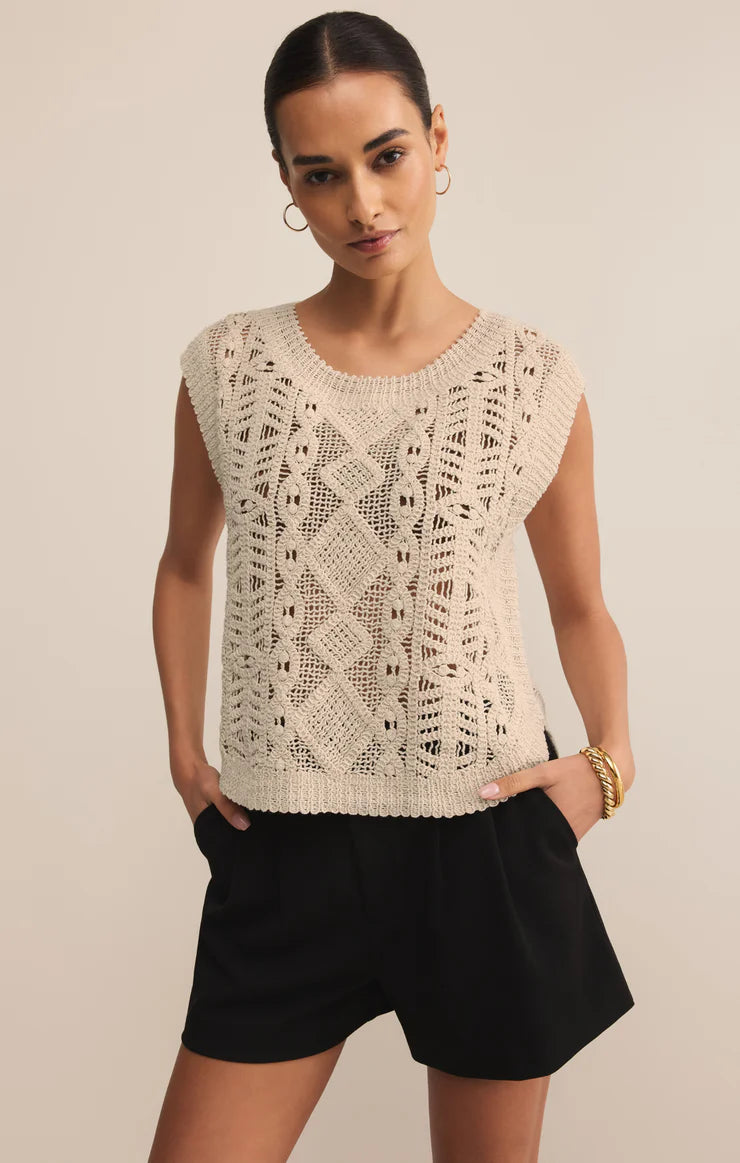Woman wearing a sleeveless crochet top and black shorts against a beige background