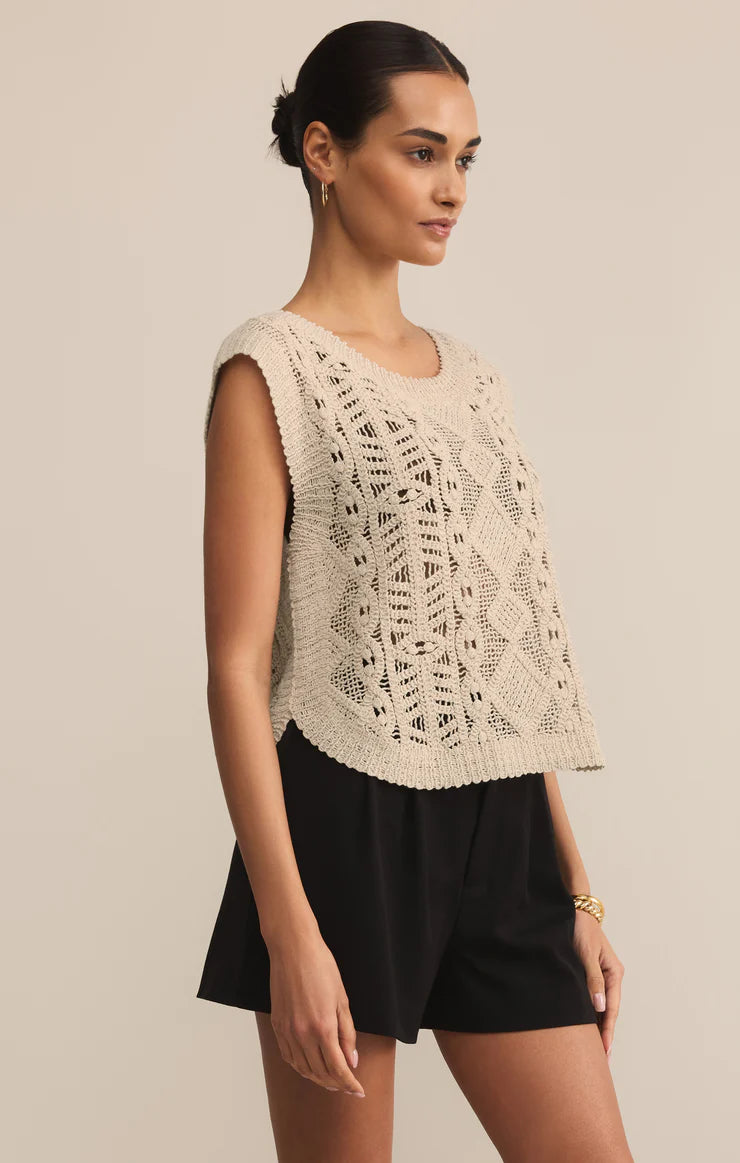 Woman wearing a beige lace top and black shorts against a beige background